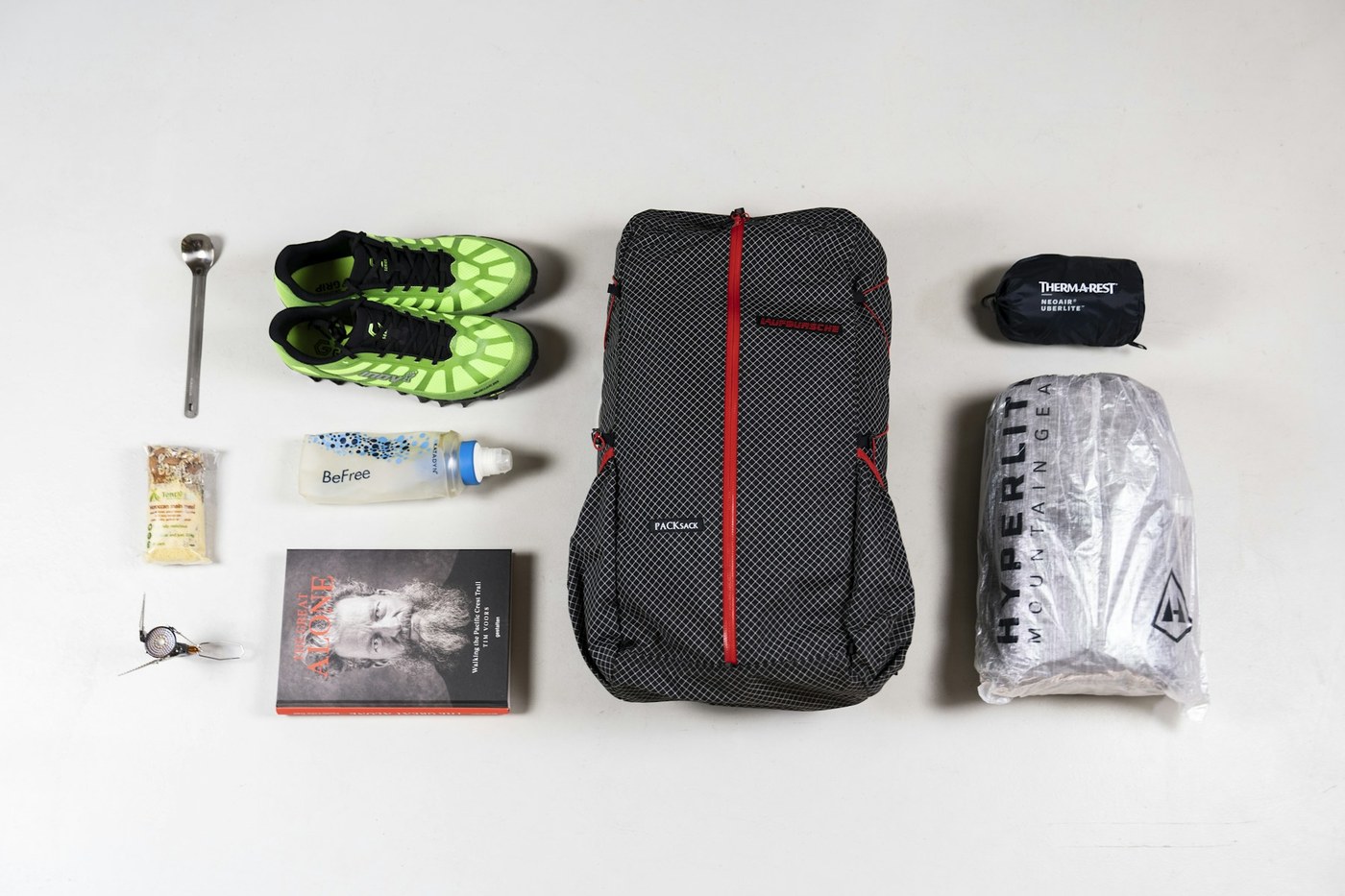 Open bug-out backpack on a wooden table with survival gear carefully organized around it