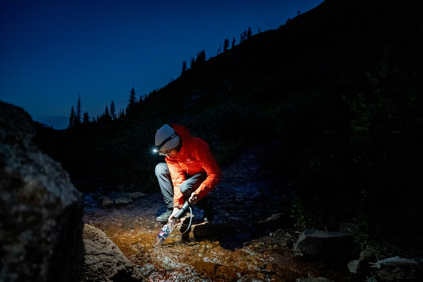 Hiker filtering water from a mountain stream using a portable water filter